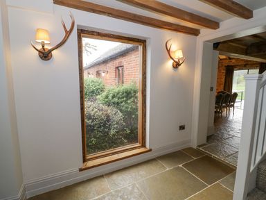 A hallway with antler wall lamps and a window looking out to bushes at Fairoaks Barns in Hollybush near Ledbury