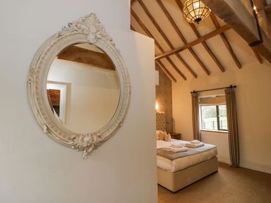 A bedroom with a bed folded towels a window and a round decorative mirror on a wall at Fairoaks Barns Hollybush near Ledbury