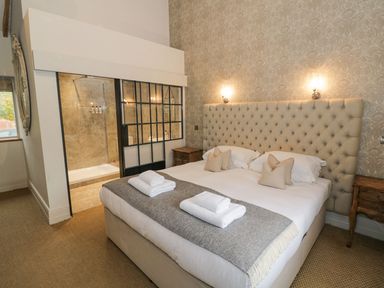 A bedroom with a large bed with pillows and towels and an en suite bathroom at Fairoaks Barns Hollybush near Ledbury