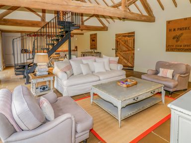 A living room with sofas a coffee table a side table and a spiral staircase at Fairoaks Barns in Hollybush near Ledbury