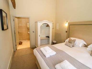 A bedroom with a bed and folded towels next to a white cabinet and an open door leading to a bathroom at Fairoaks Barns in Hollybush near Ledbury