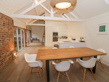 A kitchen and dining area with a wooden table and white chairs at Fairoaks Barns in Hollybush near Ledbury
