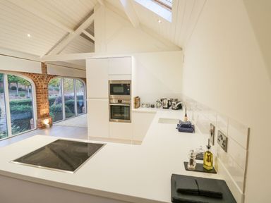 A modern kitchen with white countertops appliances and large windows showing garden at Fairoaks Barns Hollybush near Ledbury
