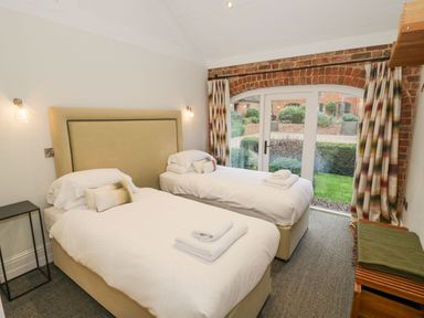 A bedroom with two single beds and a large window with curtains at Fairoaks Barns in Hollybush near Ledbury