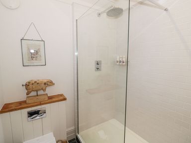 A bathroom with a glass shower enclosure wooden pig sculpture and framed art at Fairoaks Barns Hollybush near Ledbury