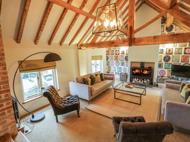 A living room with sofas a fireplace and a glass coffee table at Fairoaks Barns in Hollybush near Ledbury