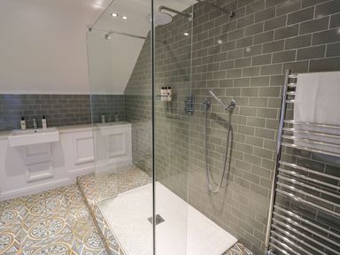 A bathroom with a walk in shower with glass enclosure a sink with bottles and a towel rack with a towel at Fairoaks Barns Hollybush near Ledbury