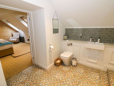 A bathroom with toilet sink and mirror with patterned floor tiles at Fairoaks Barns in Hollybush near Ledbury