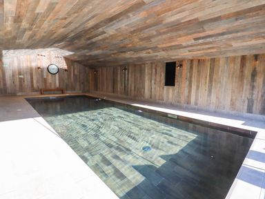 An indoor swimming pool with wooden walls and ceiling at Fairoaks Barns in Hollybush near Ledbury