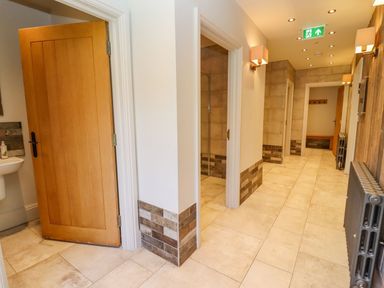 A corridor with multiple doorways and wall lights at Fairoaks Barns in Hollybush near Ledbury