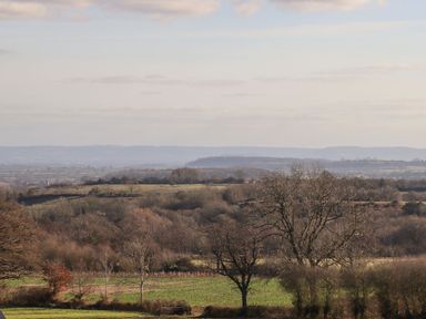 A landscape with leafless trees and green fields under a cloudy sky at Fairoaks Barns in Hollybush near Ledbury
