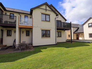 Exterior view of a building with balconies and outdoor seating on a lawn at Mallard Cottage in Penrith