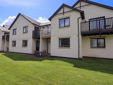 Exterior view of a two story building with balconies and a patio table with chairs on a lawn at Mallard Cottage in Penrith