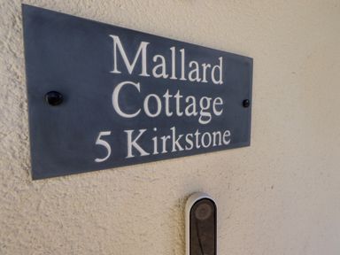 A wall with a sign reading Mallard Cottage 5 Kirkstone and a doorbell camera at Mallard Cottage in Penrith
