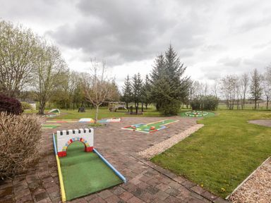 An outdoor mini golf course with pathways trees and grass at Mallard Cottage Penrith