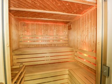 An empty wooden sauna room with tiered benches and soft lighting