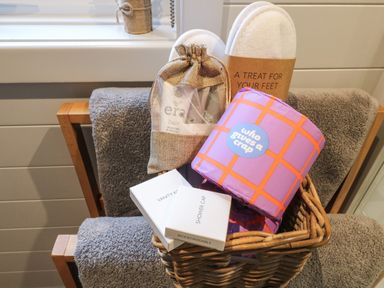 A basket with toiletries vanity kit shower cap slippers and a roll of toilet paper on a towel rack at No Deer in Ashbourne