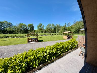 An outdoor area with grassy fields and wooden shelters at No Deer in Ashbourne
