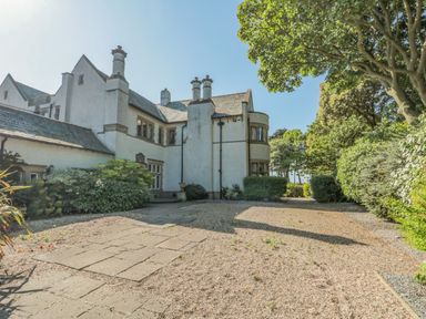 An exterior view of a white multi-story house with chimneys surrounded by trees at Highcliffe Manor in Flamborough
