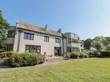 The exterior of a multi-story house with windows bushes and a lawn at Highcliffe Manor in Flamborough