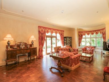 A living room with patterned sofas tables lamps and large windows at Highcliffe Manor in Flamborough