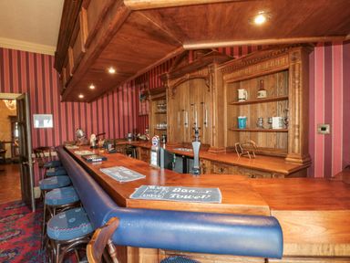 A traditional wooden bar area with stools and shelves stocked with mugs and glasses at Highcliffe Manor in Flamborough