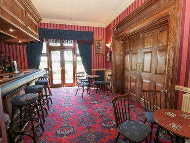 A room with a bar counter and stools a patterned carpet and wooden sliding doors at Highcliffe Manor in Flamborough