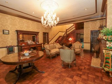 A sitting room with antique furniture wooden staircase and chandelier at Highcliffe Manor in Flamborough
