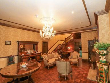 A sitting room with vintage furniture a chandelier and a wooden staircase at Highcliffe Manor in Flamborough