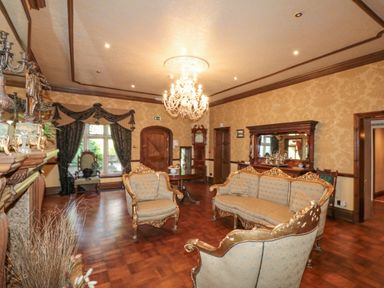 A sitting room with ornate sofas a chandelier a grandfather clock and wooden furniture at Highcliffe Manor in Flamborough
