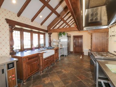 A kitchen with wooden cabinets tiled floor wooden beams and stainless steel appliances at Highcliffe Manor in Flamborough