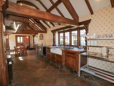 A kitchen with wooden beams on the ceiling wooden cabinets a farmhouse sink and a wooden dining table with chairs at Highcliffe Manor in Flamborough