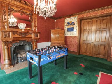 A room with a foosball table green carpet wooden fireplace and a wooden cabinet at Highcliffe Manor in Flamborough