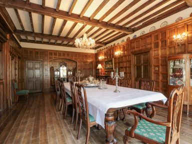 A dining room with a long table covered with a white tablecloth and wooden chairs at Highcliffe Manor in Flamborough