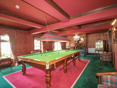 A room with a snooker table and foosball table surrounded by chairs and wooden furniture at Highcliffe Manor in Flamborough