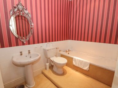 A bathroom with a pedestal sink toilet and bathtub with a towel hanging on it at Highcliffe Manor in Flamborough