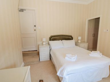 A bedroom with a double bed between two bedside tables with lamps towels on the bed and a door to a bathroom at Highcliffe Manor in Flamborough