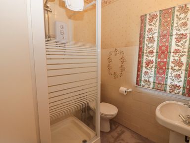 A bathroom with a shower cubicle toilet sink and floral curtain at Highcliffe Manor in Flamborough
