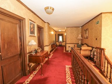 A hallway with red carpet wooden doors and antique furniture at Highcliffe Manor in Flamborough