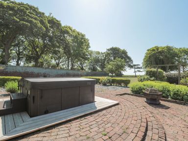 An outdoor patio area with a hot tub surrounded by brick paving and greenery at Highcliffe Manor in Flamborough