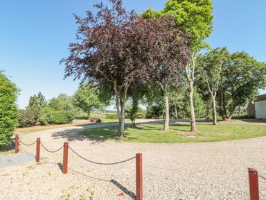 A gravel driveway curving around a group of trees with chains on red posts at Highcliffe Manor in Flamborough