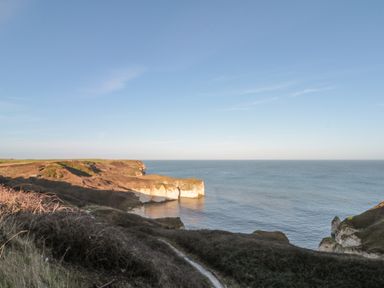 A coastal cliff landscape with a path and sea at Highcliffe Manor in Flamborough