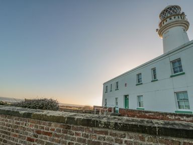 A white lighthouse and building behind a brick wall at Highcliffe Manor in Flamborough