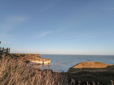 A coastal landscape with cliffs and sea under a clear sky at Highcliffe Manor in Flamborough