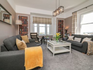 A living room with two dark sofas a white coffee table yellow flowers and two armchairs at The Outlook in Minehead