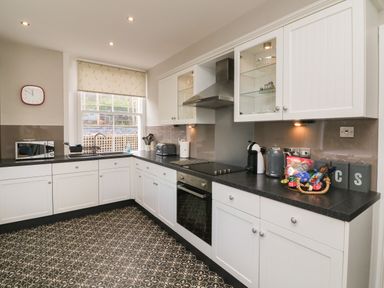A kitchen with white cabinets black countertops a stove microwave and a window at The Outlook in Minehead