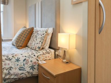 A bedroom with a bed two pillows a bedside table with a lamp and a wardrobe door at The Outlook in Minehead
