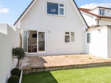A backyard patio with paved area and artificial grass outside a white house at The White House in Weymouth