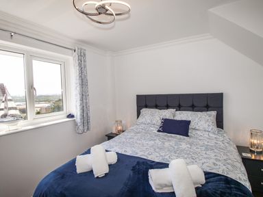 A bedroom with a bed with floral bedspread and rolled towels on a blanket at The White House in Weymouth