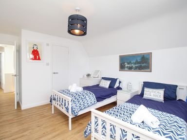 A bedroom with two single beds with blue bedding a nightstand and wooden flooring at The White House in Weymouth